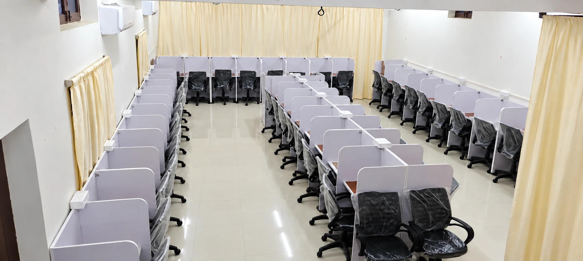 Wide view of rows of numbered study cabins at Sadhana Study Hall